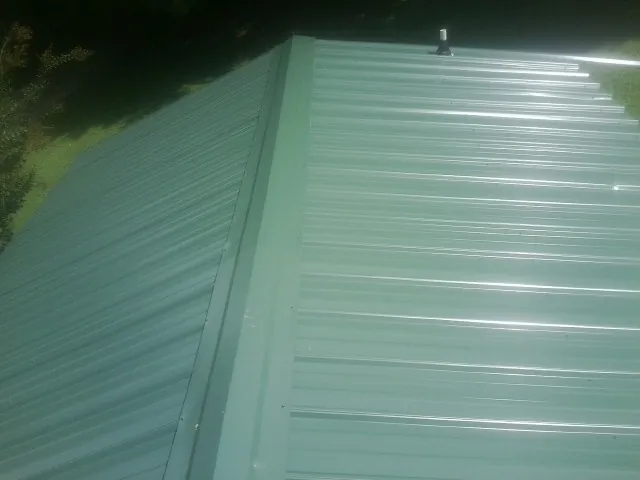 New green metal panels meeting at the ridge of a roof — Flat Roof Repair work by our crew in Weatherly