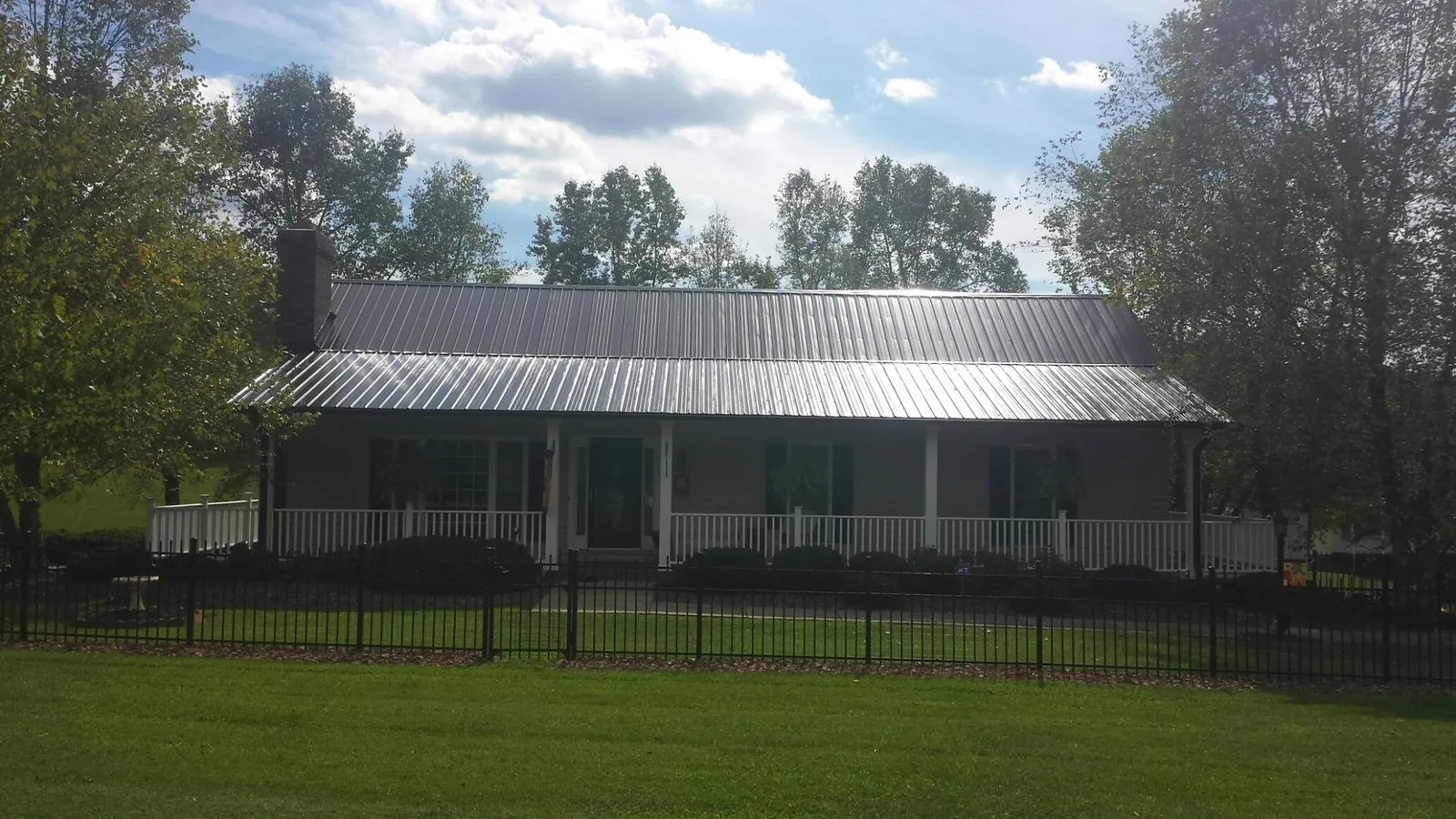 Gray metal roof on a brick ranch with a full width front porch — Gutter Guard Installation work by our crew in Weatherly