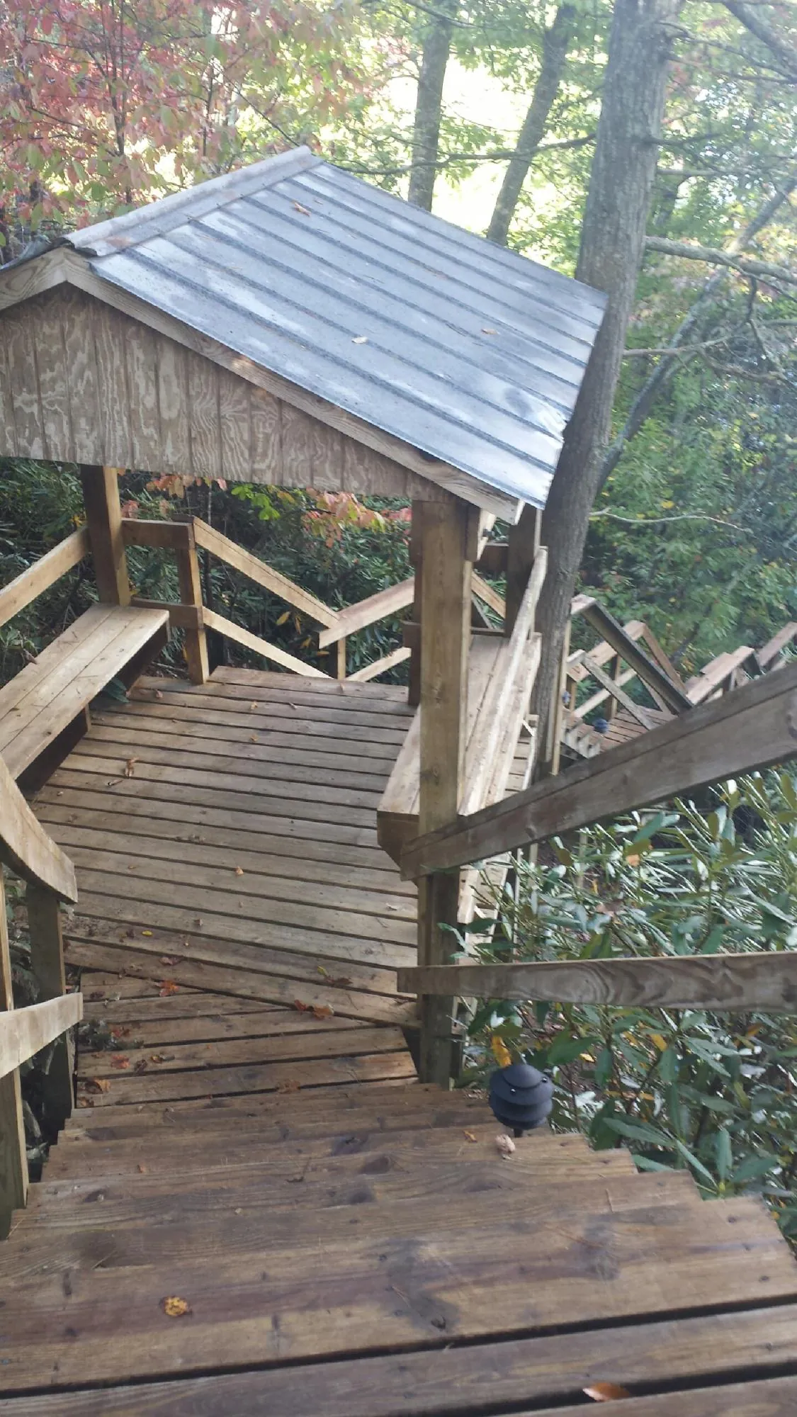 Metal roofed shelter over wooden steps on a wooded walkway — Skylight Repair & Installation work by our crew in Weatherly