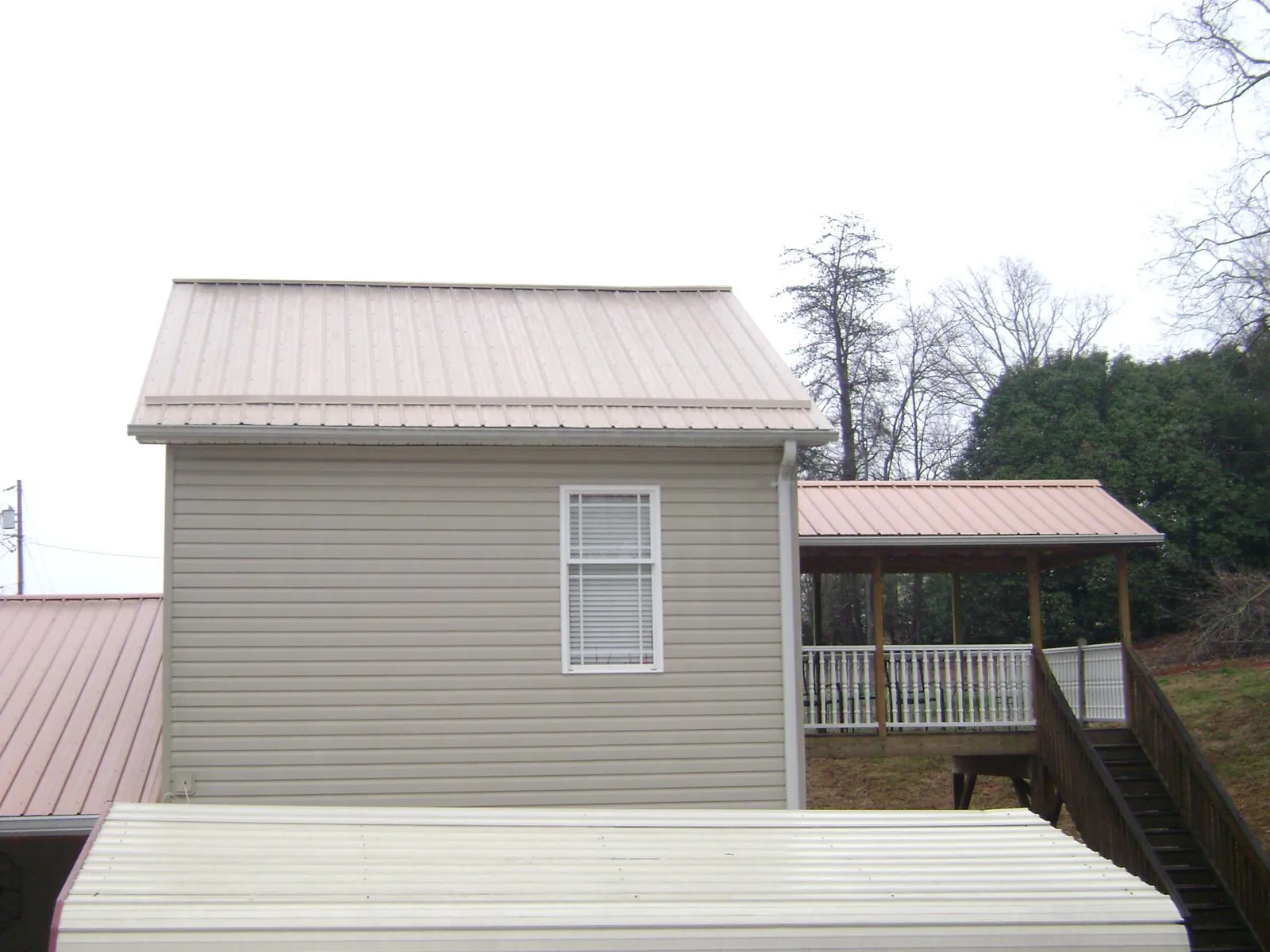 Tan metal roofs on a two story addition and attached porch, from a Roof Replacement job in Weatherly