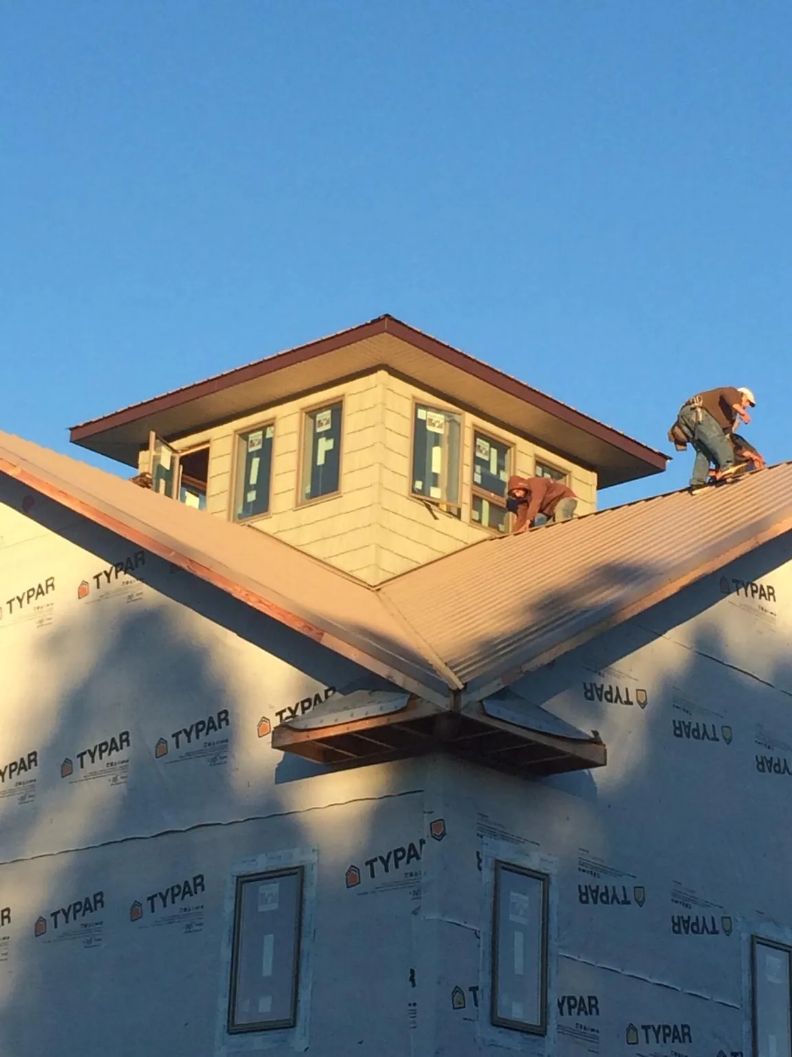 Roofers working around a rooftop cupola on a new metal roof at sunset — Roof Waterproofing in Weatherly by Roofing Brothers